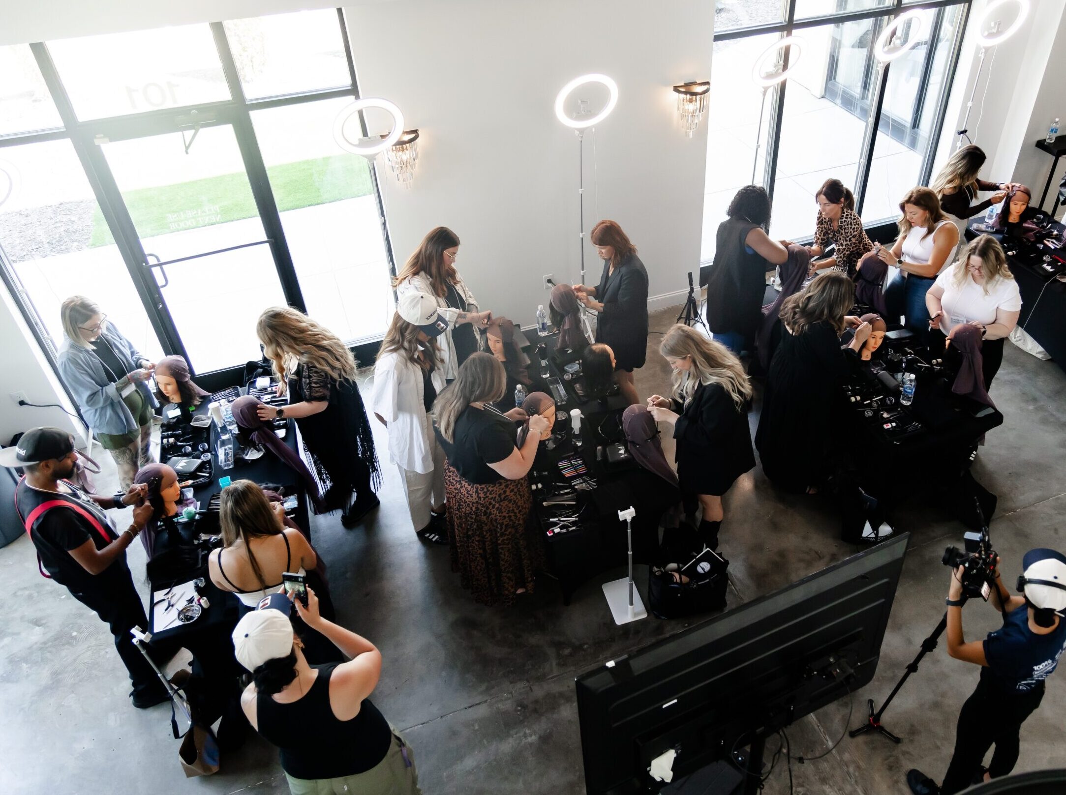 An overhead view of stylists practicing luxury hair restoration techniques during a confidence with crowns class