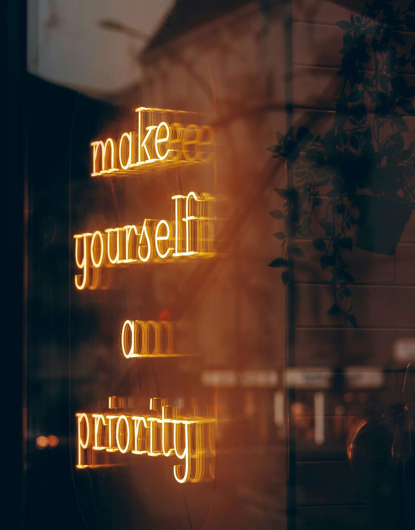 A neon sign that reads "make yourself a priority"